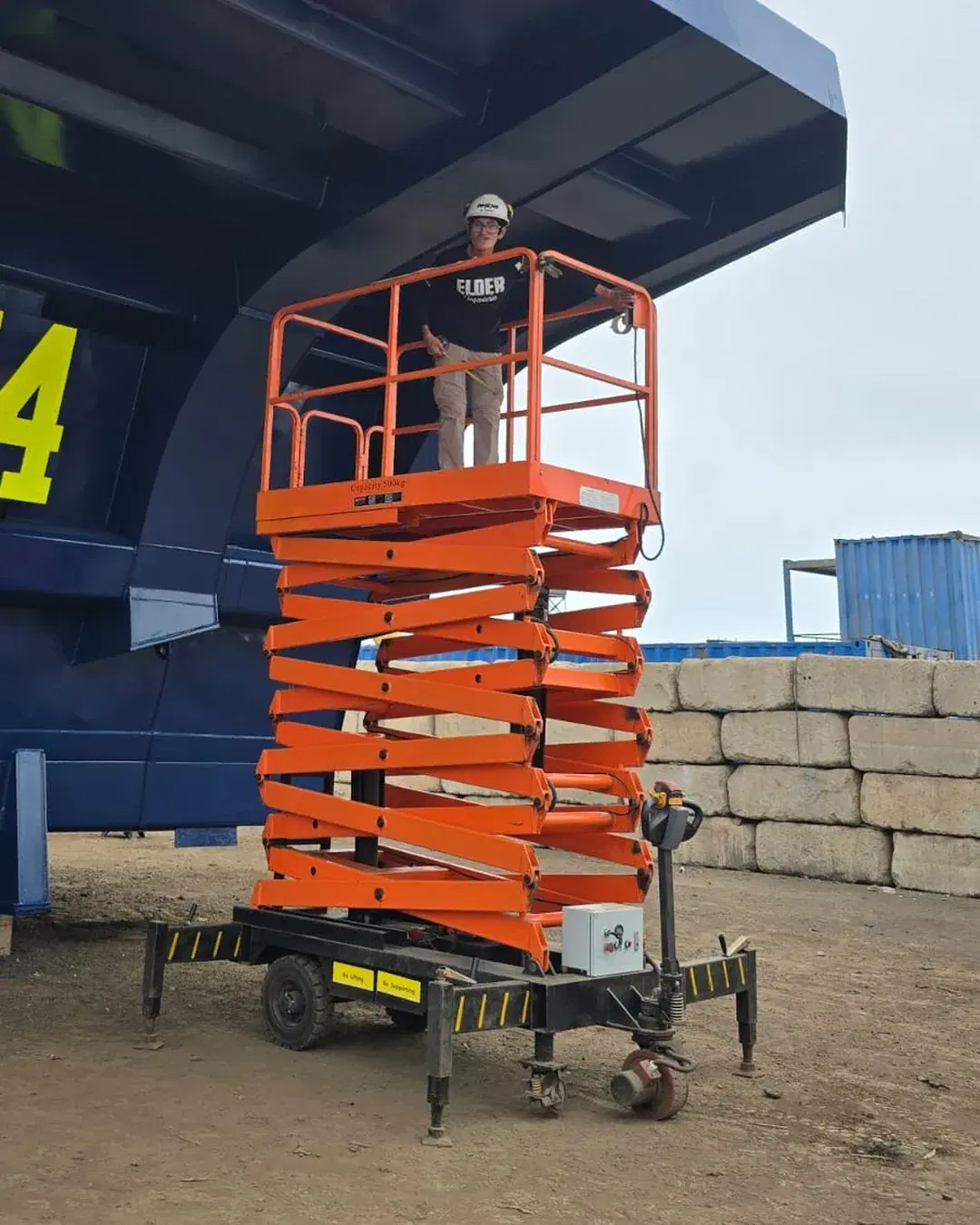 Operario con EPP trabajando arriba de la plataforma elevadora junto a la tolva de un camión minero